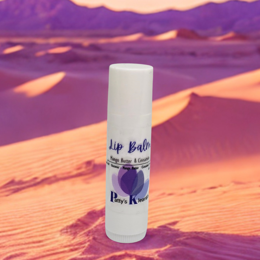 Lip balm tube with 'Patty's Kleaners' branding on a desert background. Mango Butter and Cinnamon 